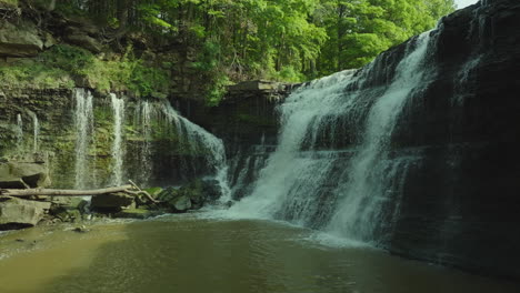 side view of waterfall captured with pan left motion highlighting lush trees and water flow