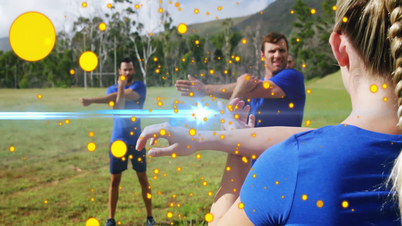 Fitness team stretching in grassy field, showing glowing orange orbs and blue lens flare