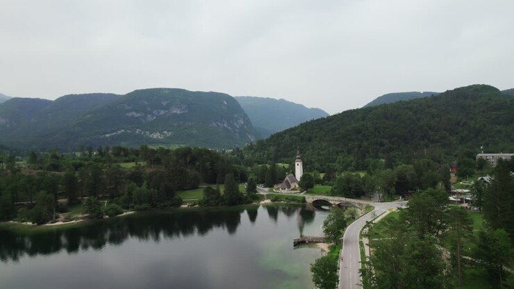 Ripresa con drone sul lago di Bohinj in Slovenia con una chiesa e montagne sullo sfondo al tramonto