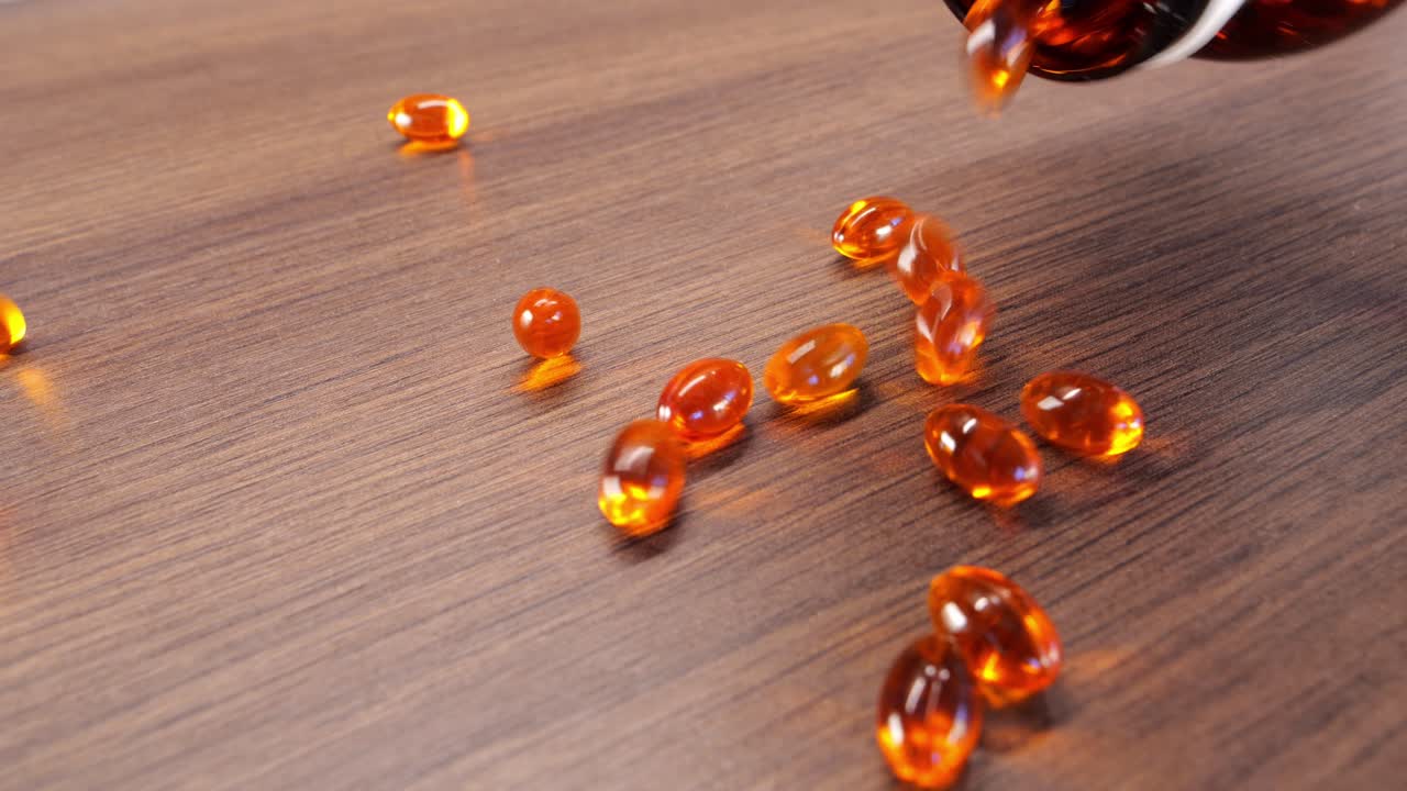 vertiendo cápsulas de naranja píldoras de omega 3 como un símbolo de sobredosis de drogas, cayendo de la jarra
