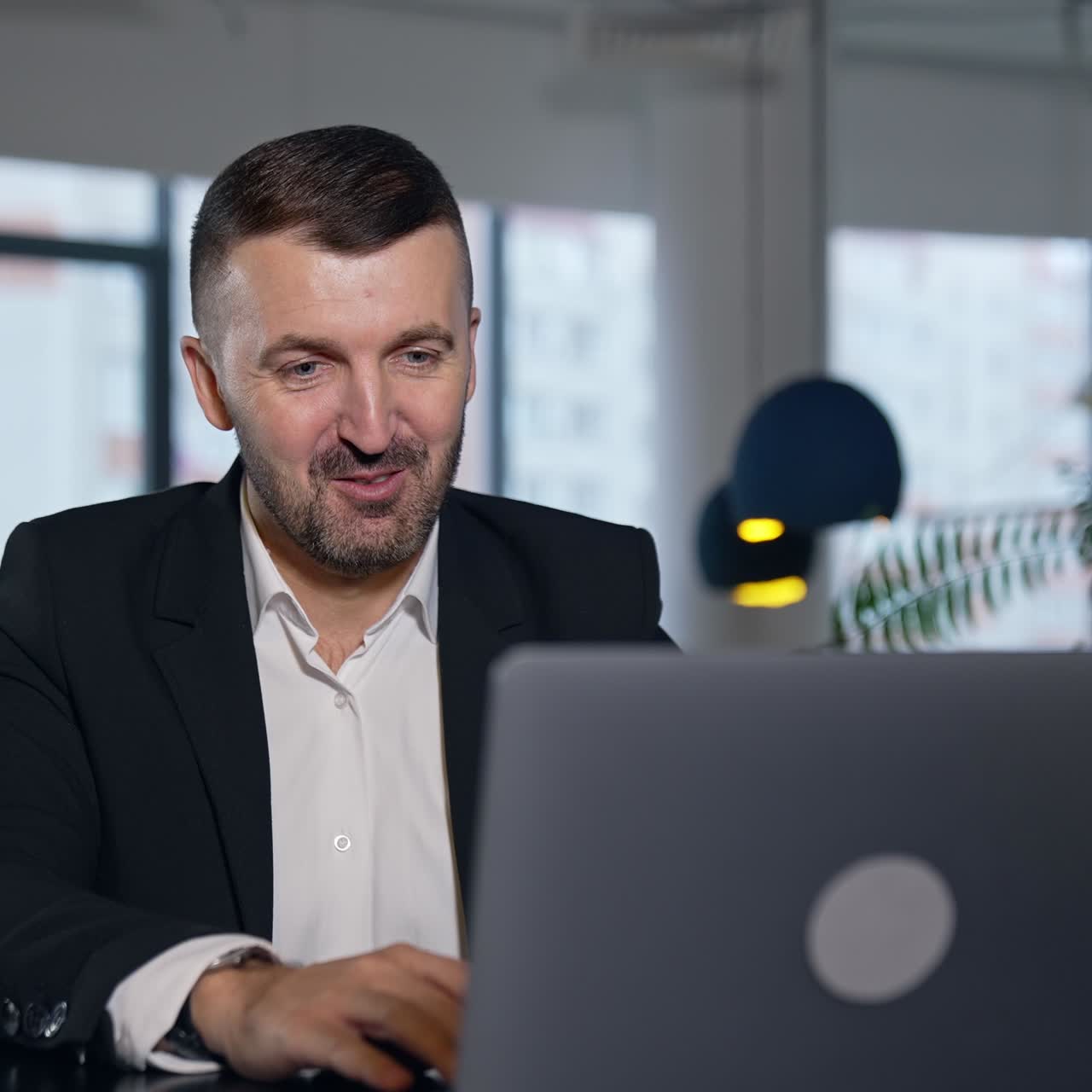 Confident male entrepreneur chatting on laptop. Man having business negotiations via internet. Blurred office background