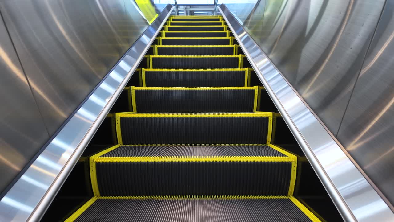 POV of an empty escalator going up in a modern building with stainless steel walls