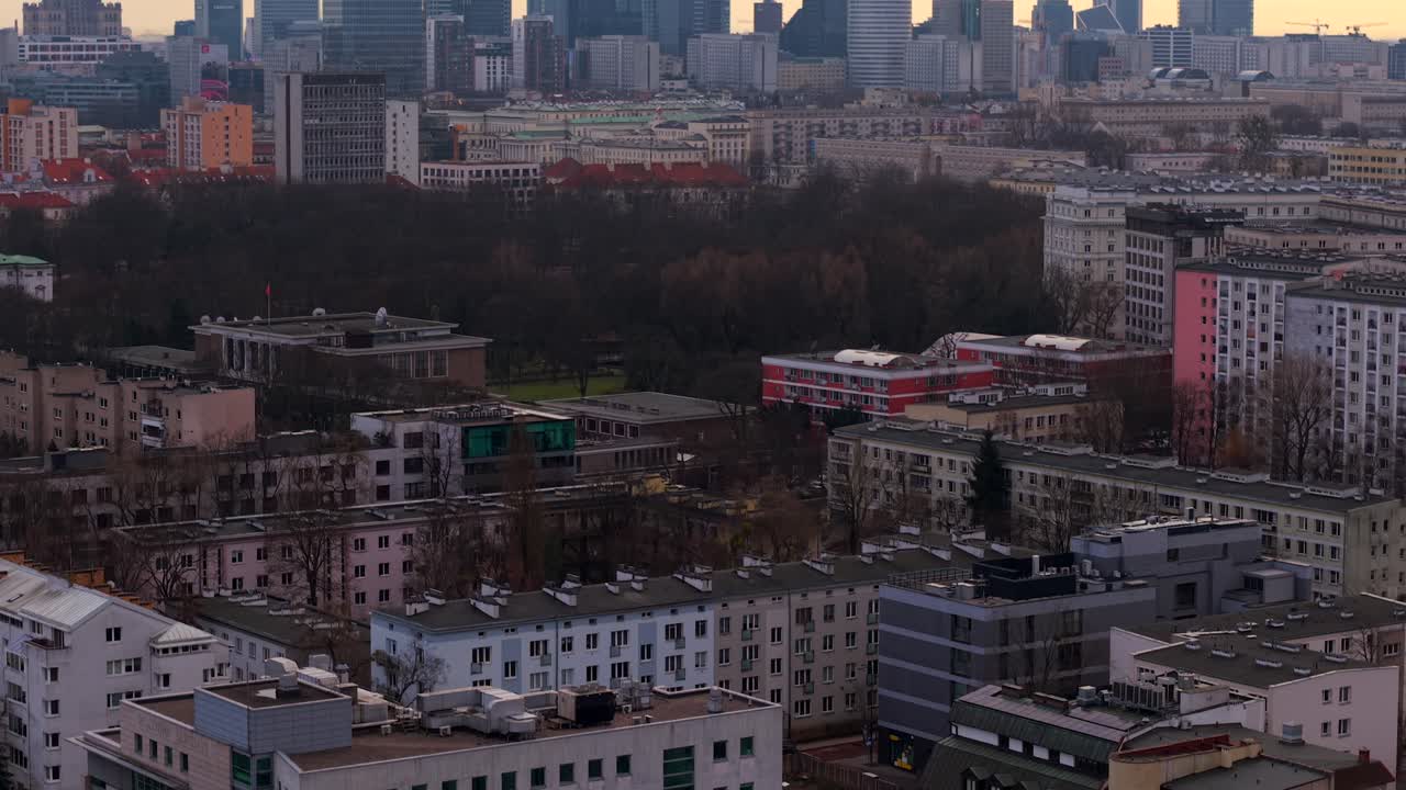 Aerial tilting up to reveal the Warsaw skyline, with Varso Tower and Palace of Culture and Science at sunset golden hour