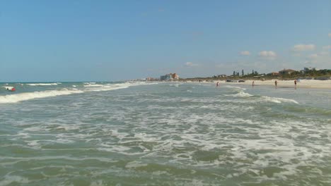 A-low-fast-forward-aerial-view-of-the-cresting-waves-at-New-Smyrna-Beach,-Florida