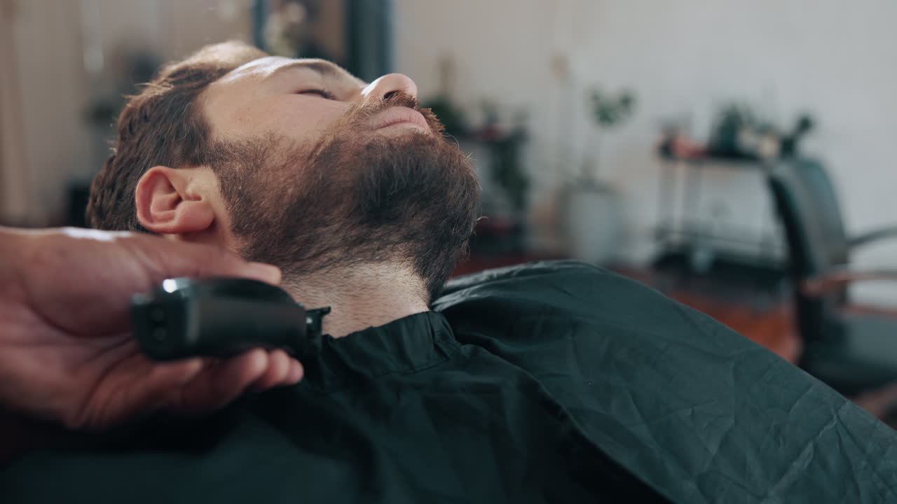 Mand får trimmet sit skæg af en barber i en salon