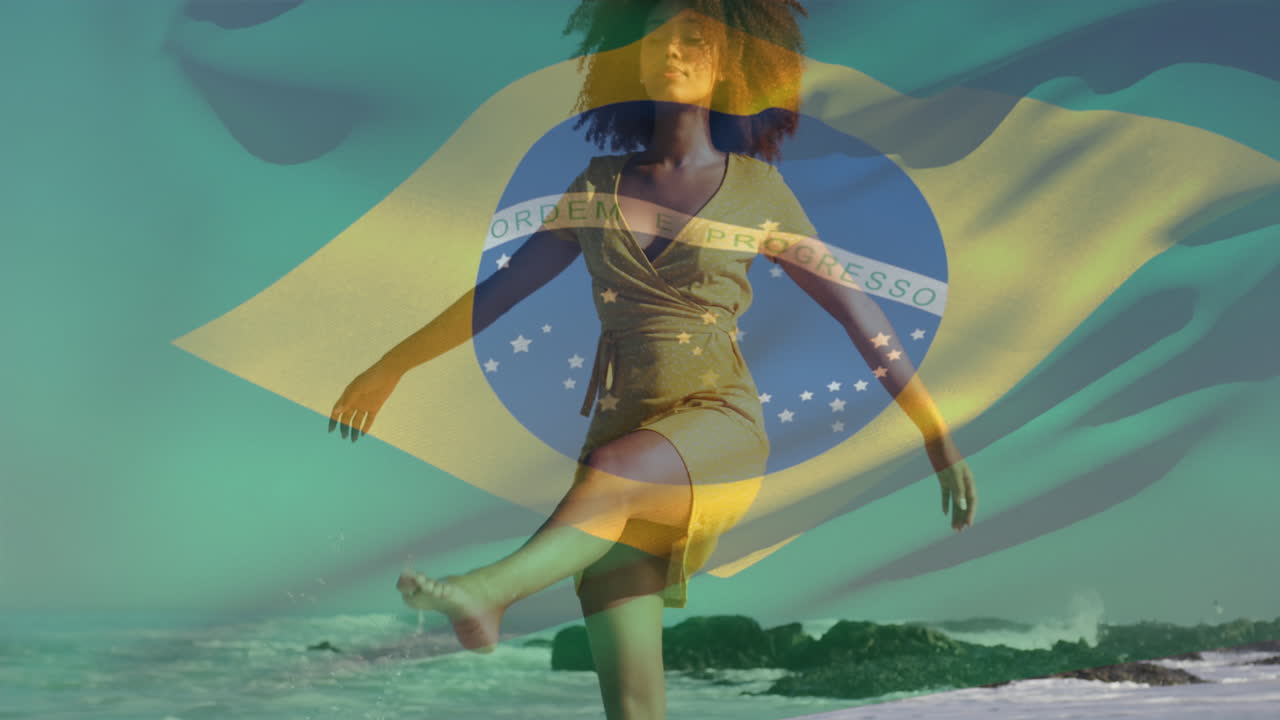 animación de una mujer biracial ondeando la bandera de brasil caminando y disfrutando de la brisa en la playa