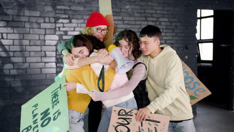 happy young environmental activists with placards and megaphone hugging and cheering after climate change protest