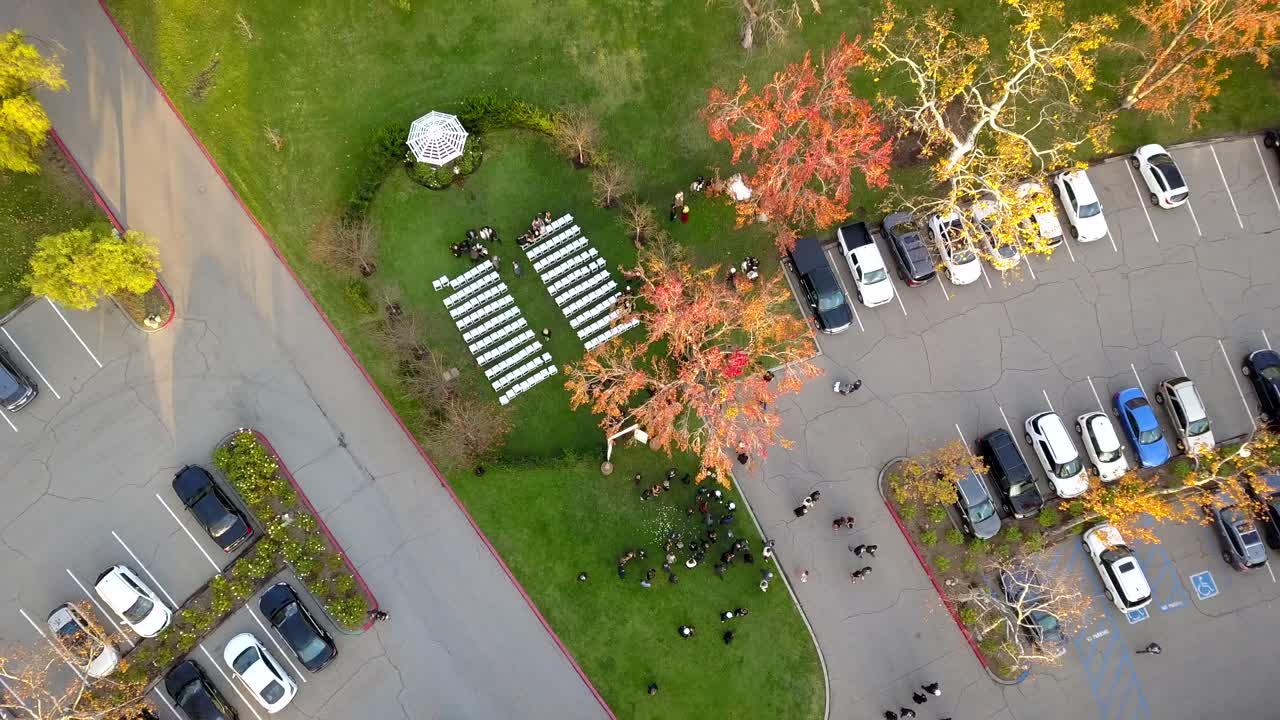 Aerial drone rising shot of people leaving an outdoor military wedding.