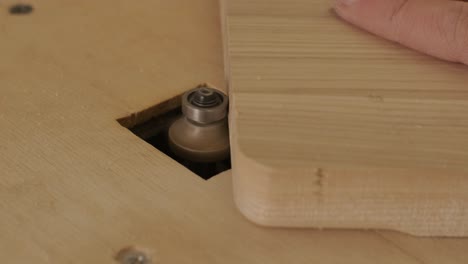 a carpenter uses a router tool for rounding the corner of the wood