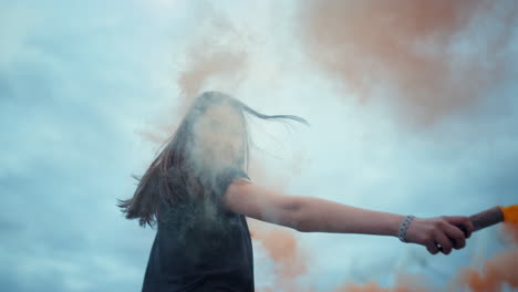 chica agitando la mano con una bomba de humo en la calle. mujer posando ante la cámara