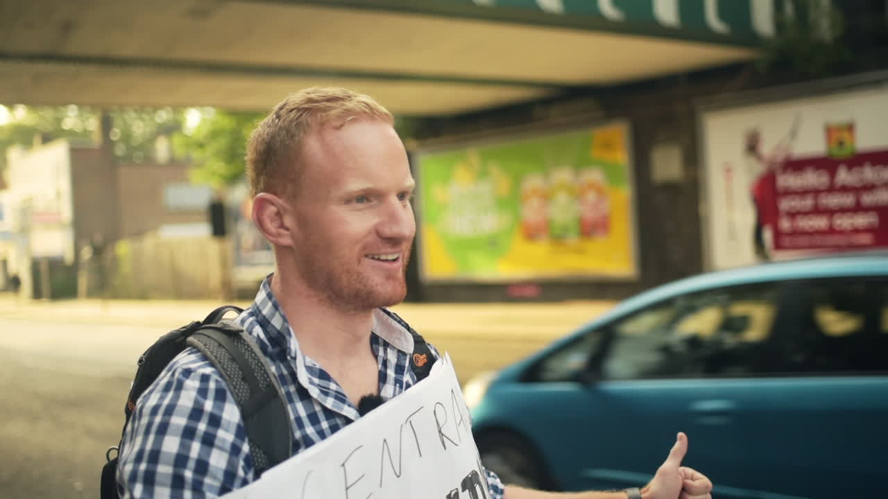 Handsome happy hitchhiker looking for a ride to central London