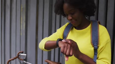 mujer afroamericana mirando un reloj inteligente en la calle