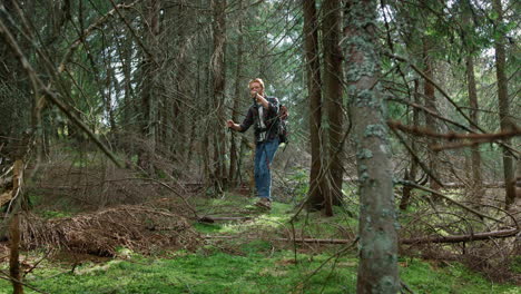 man walking with trekking poles in green forest