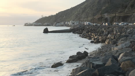 rocky stone shoreline of big rock beach malibu, next to the edge highway road at magic golden hour