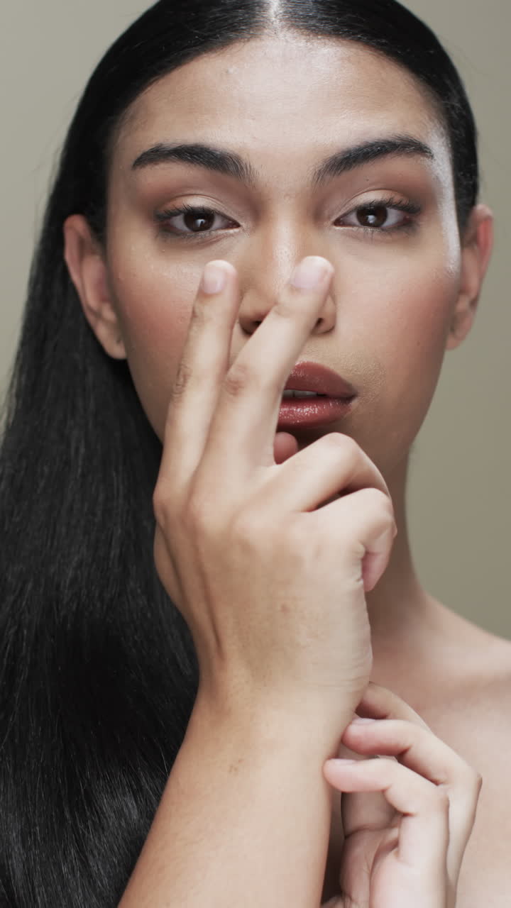 Vertical video of biracial woman with black hair, make up looking at camera, copy space, slow motion
