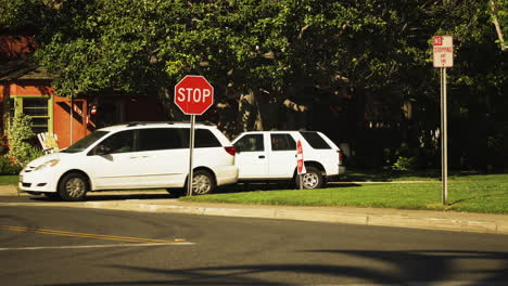 red color stop sign and white vehicle in streets of los angeles