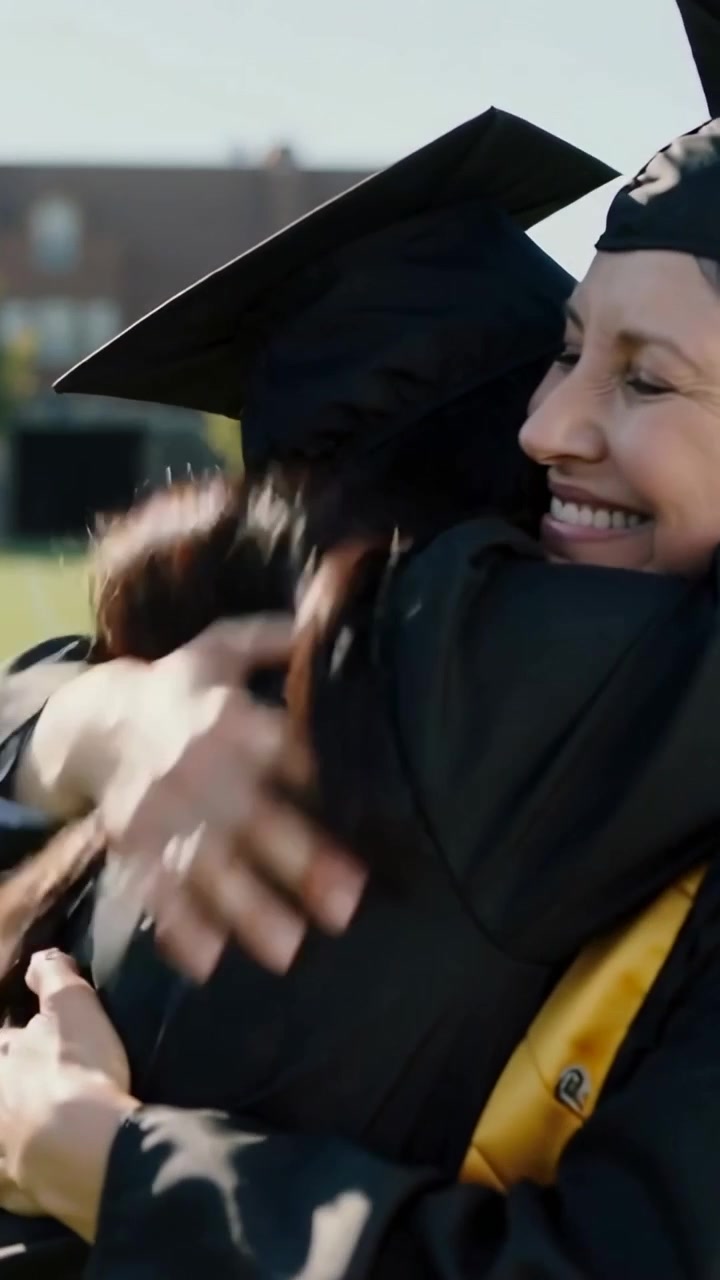 Vertical video: Walking Asian graduate hugging mentor on campus, procession cueing, maroon stole