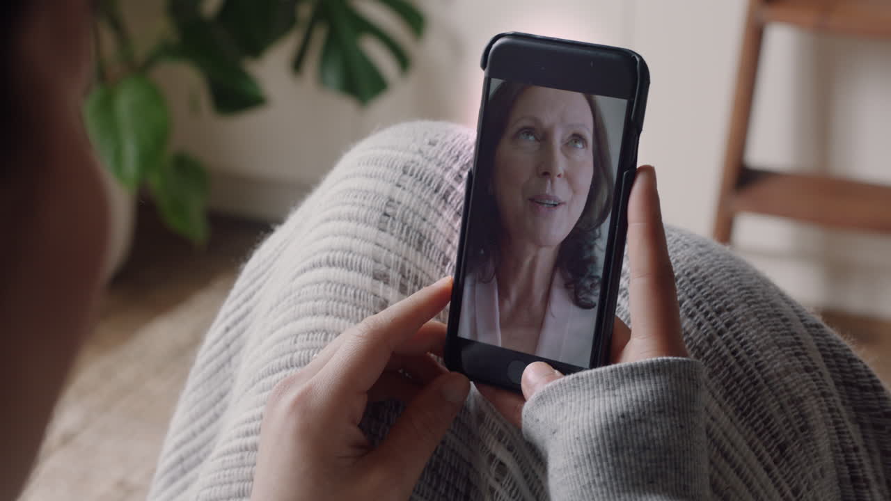 mujer joven teniendo video chat usando teléfono inteligente en casa hablando con su madre disfrutando de la conversación compartiendo estilo de vida en el teléfono móvil
