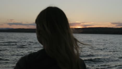 vista trasera de una joven turista relajándose en la playa al atardecer