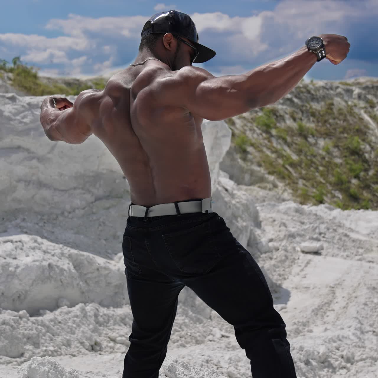 Motion camera view of the athletic young shirtless bodybuilder with naked torso posing for camera and showing his body