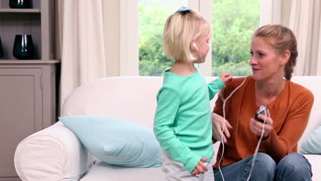 cute little girl listening to music with her mother