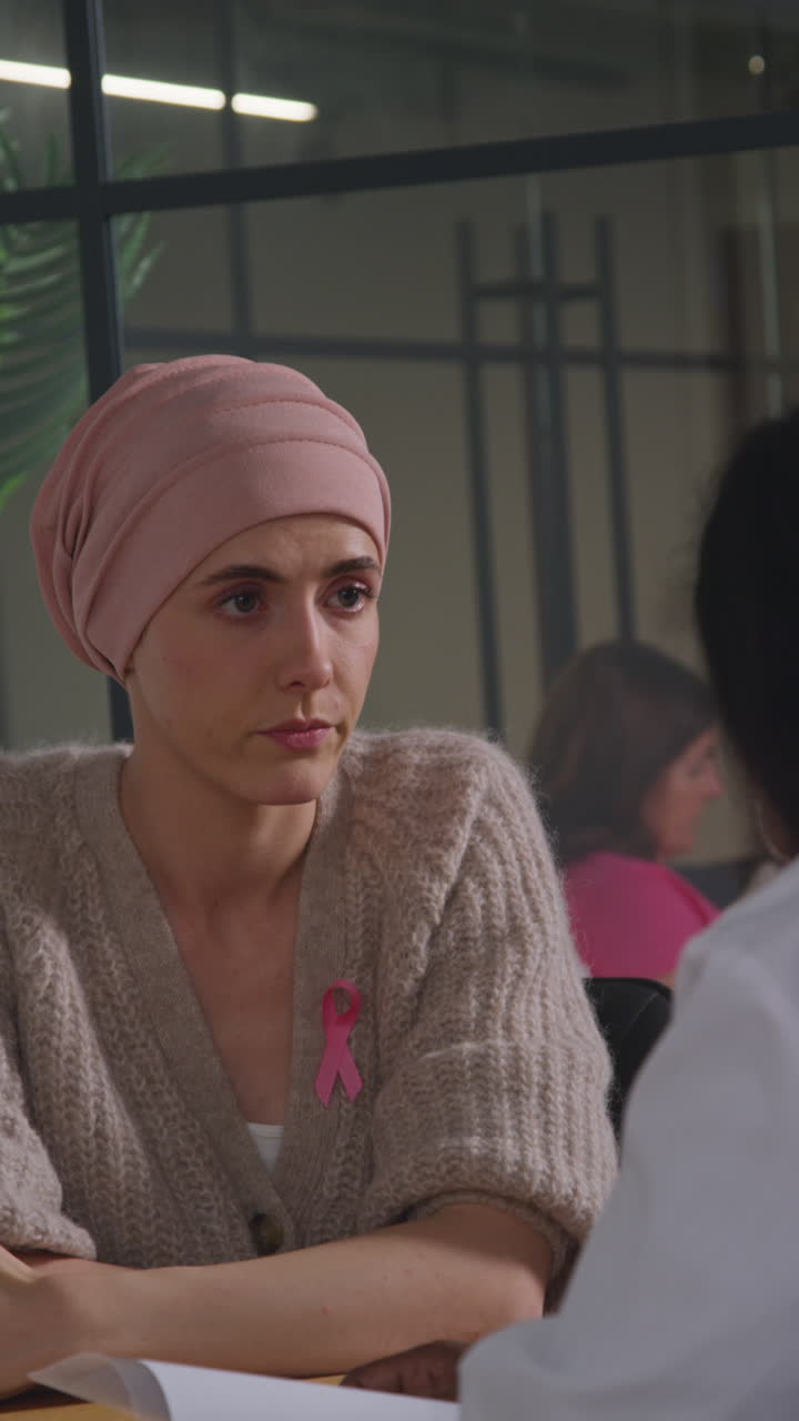 Vertical Video Of Serious Young Woman Patient Wearing Headscarf Undergoing Chemotherapy Treatment For Breast Cancer Meeting With Oncologist Or Doctor In Hospital 1