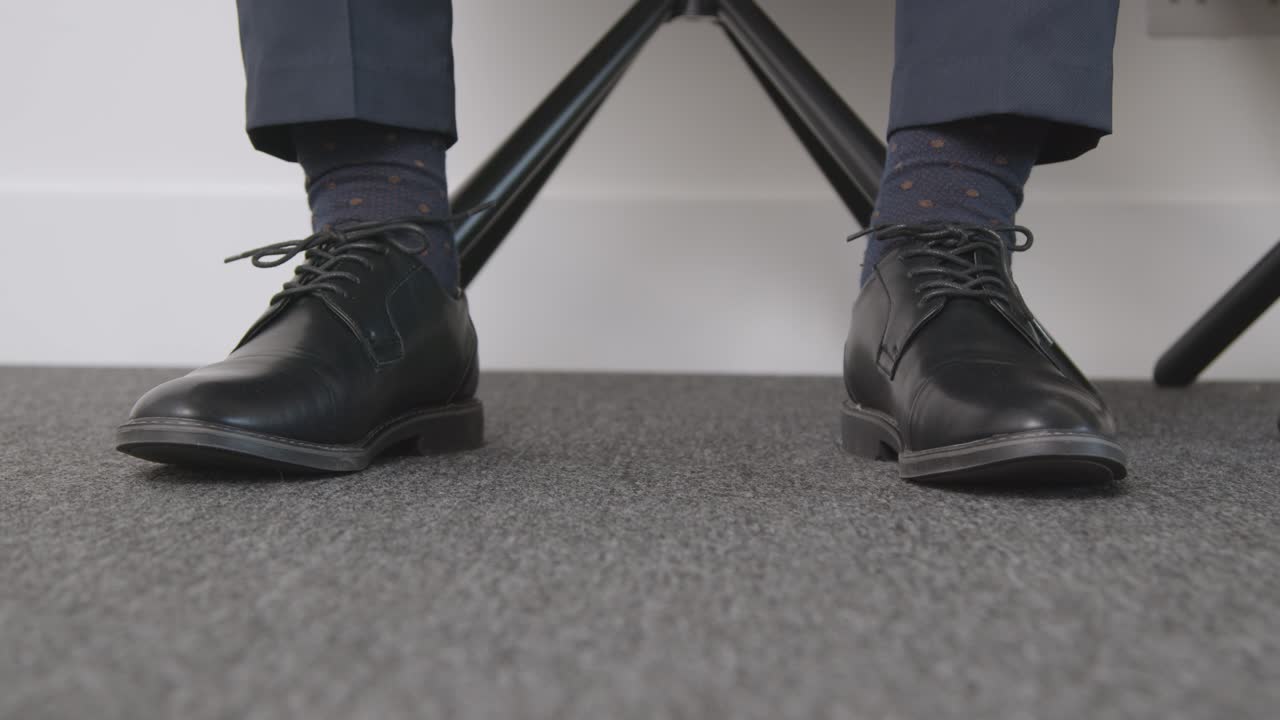 primer plano de los pies del candidato masculino esperando en el cargo antes de la entrevista de trabajo 1