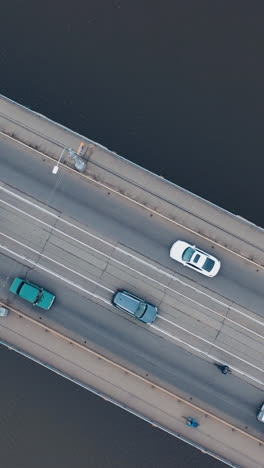 urban car traffic on the bridge over the river. shooting with a drone. vertical video