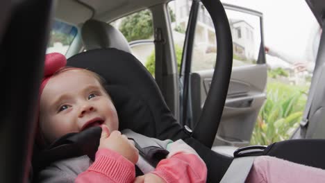 madre caucásica cerrando la puerta después de mantener a su bebé en el asiento de seguridad en el coche