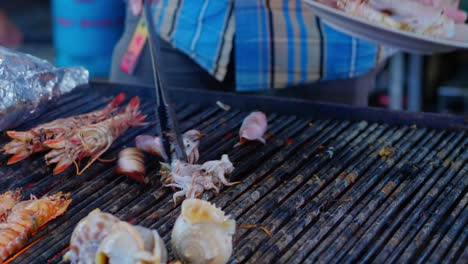 Person-serving-fresh-squid-and-mollusks-on-plate-at-Asian-street-market