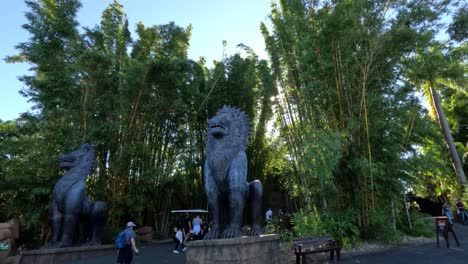 visitors walking near large statues and bamboo