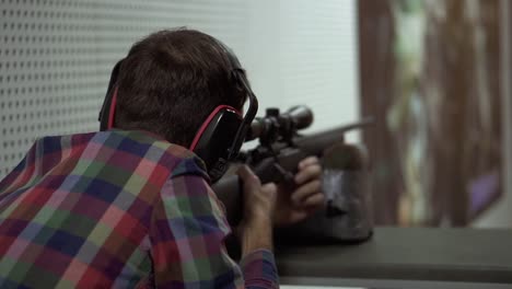 close up of a man shooting use rifle at shooting range in headphones