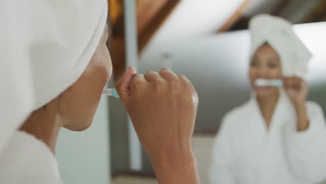 mixed race woman looking at mirror brushing teeth