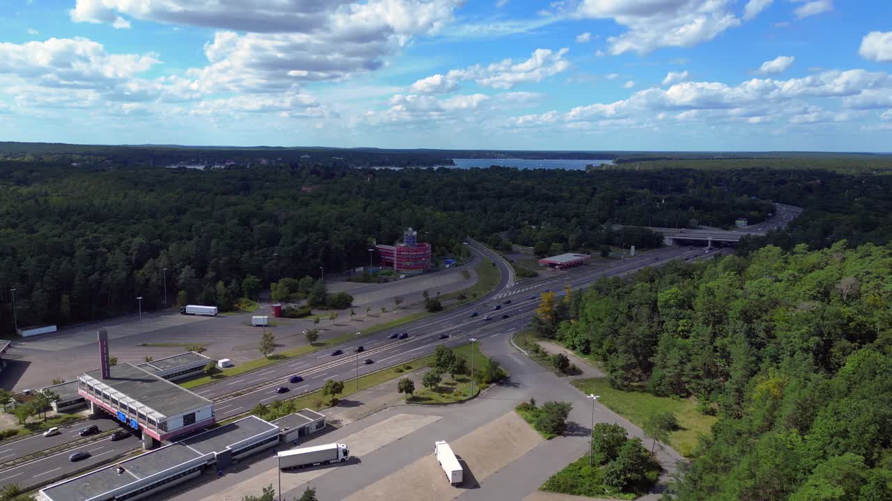 Cars driving on a freeway interchange surrounded by forest leading to a lake on a cloudy day