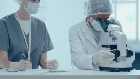 dos científicas mujeres haciendo investigación de laboratorio con microscopio