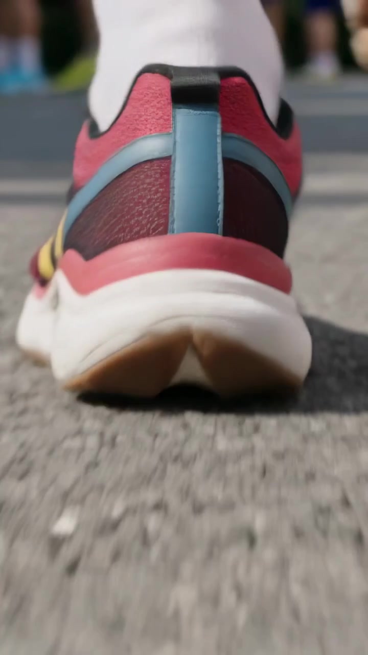 Video verticale: Scarpa da corsa che si solleva all'inizio della falcata, stacco della punta dal terreno durante una corsa di gruppo, calzini sportivi bianchi