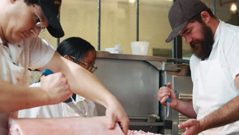 butcher showing a colleague how to prepare a cut of meat