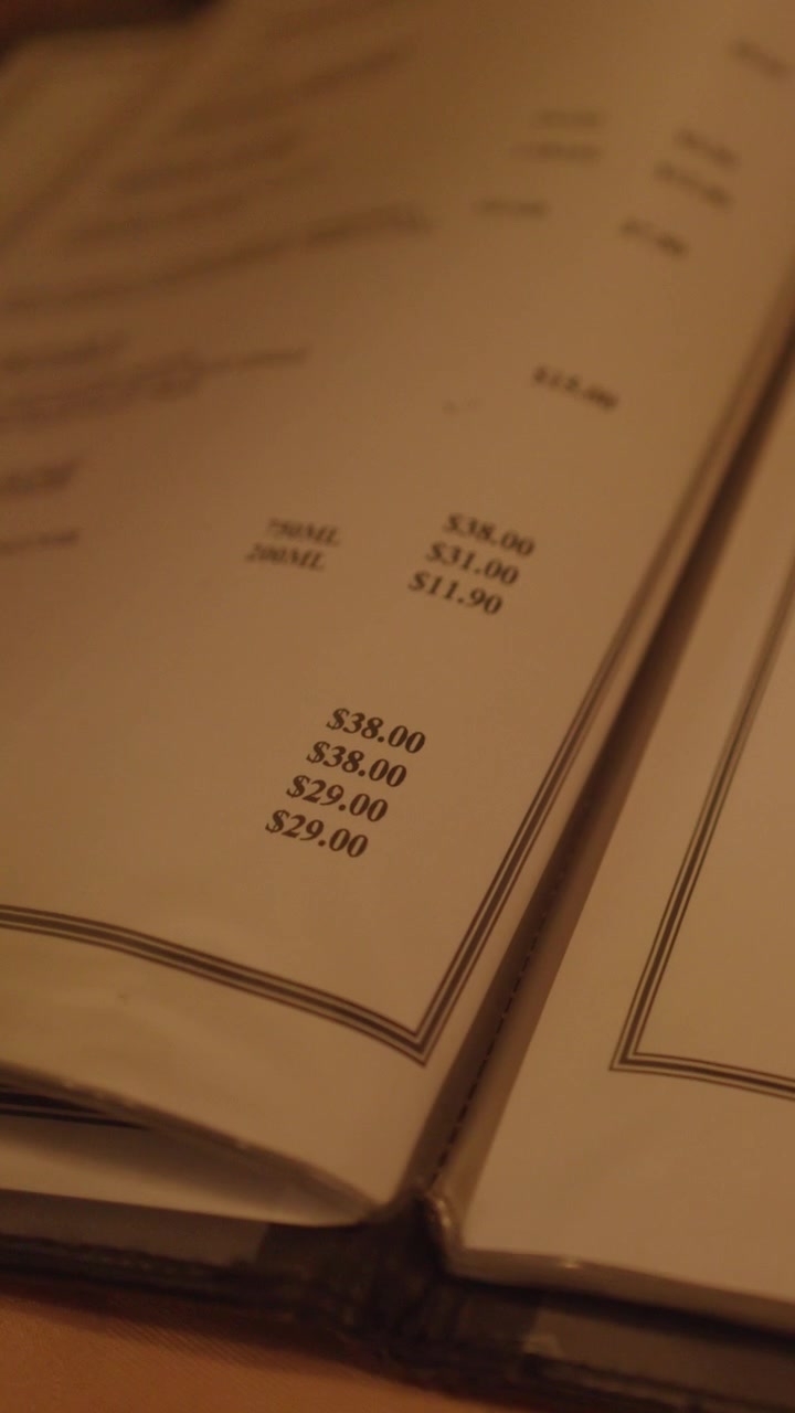 Hand flips through Chinese restaurant menu pages under soft, warm ambient lighting, close-up view