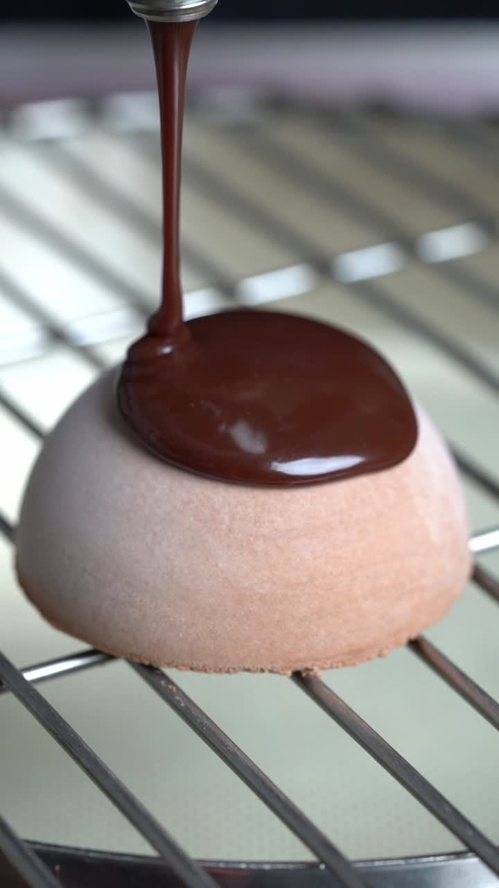 A chef puts chocolate sauce on a dessert on a white plate, close up shot. insert shot