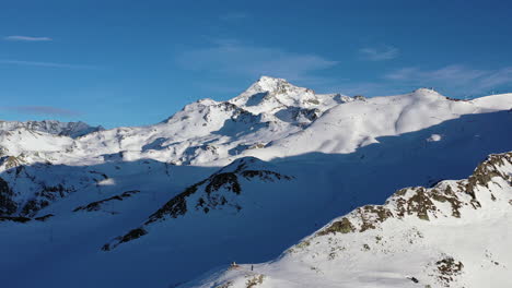 Drone-shot-flying-towards-snow-covered-mountain-peaks-in-La-Plagne,-in-the-French-Alps