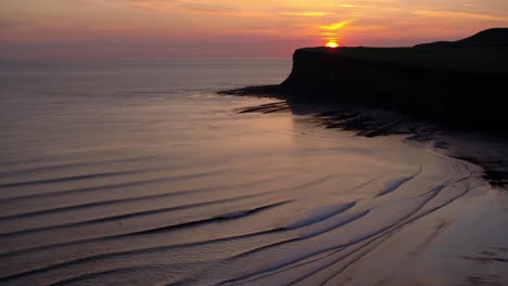 Saltburn-by-the-Sea,-early-morning-sunrise-behind-Huntcliff-headland---Aerial-Drone-DJI-Inspire-2