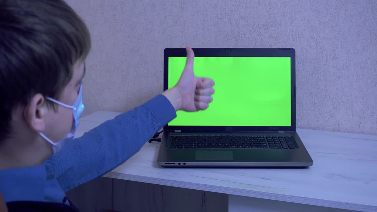 A guy in a protective face mask communicates on a video conference and gestures with his hands, remote communication during a pandemic