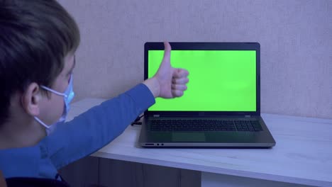 a guy in a protective face mask communicates on a video conference and gestures with his hands, remote communication during a pandemic