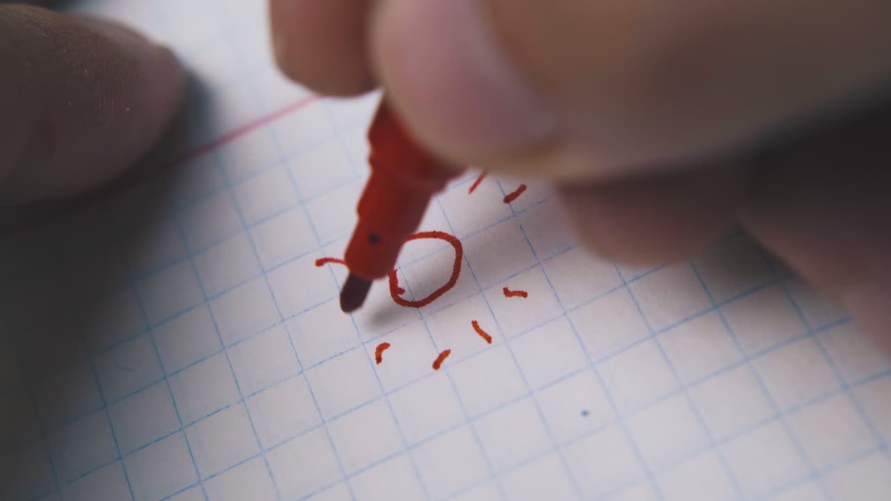 한 사람 이  ⁇ 색 체크 종이 에 빨간 마커 를 사용 하여 태양 을 그린다