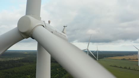 Primer-Plano-único-De-Un-Aerogenerador-Giratorio-Con-Parque-De-Aerogeneradores-En-El-Fondo