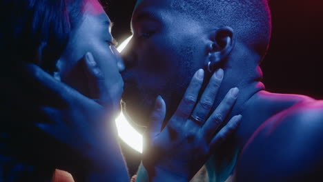 sensual couple kissing under colorful neon lights