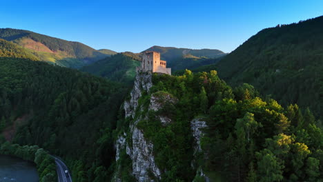 castle perched on a hill at sunrise. a majestic castle stands atop a steep hill, surrounded by lush green trees and mountains in the early morning light