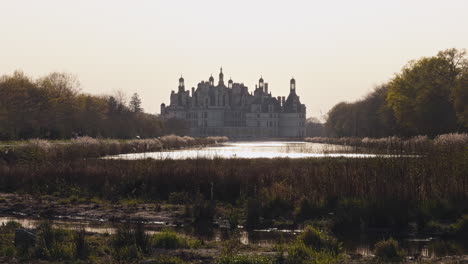 majestic castle view with calm river, tourists, and nature at golden hour