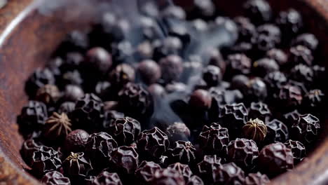 granos de pimienta negra ahumados en un cuenco de madera