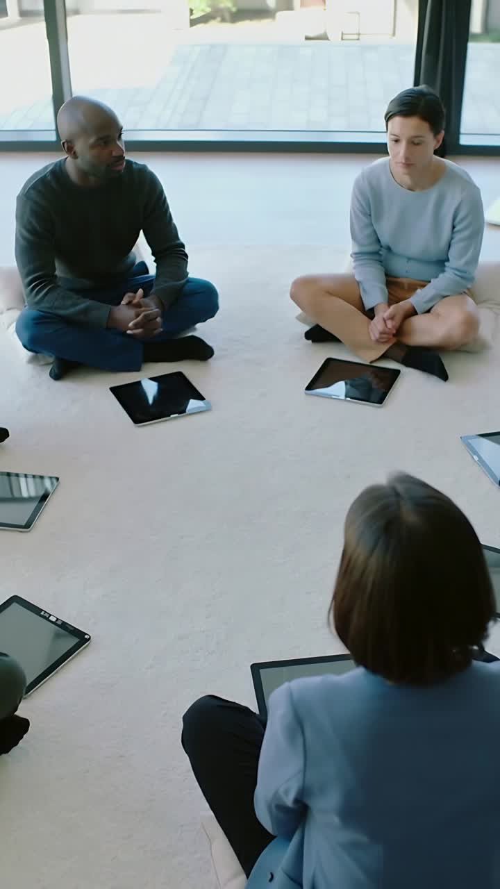 Vídeo vertical: Começando com tablets posicionados, homem com as mãos unidas, conduzindo uma conversa de jeans escuro e blusa escura em casa